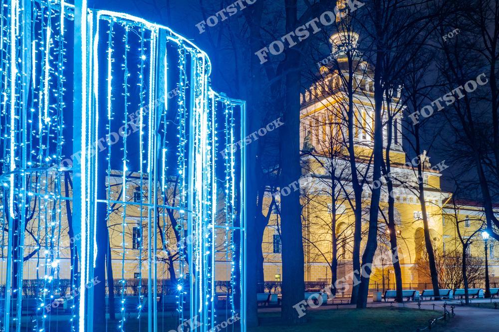 На фотографии изображено здание Адмиралтейства в Санкт-Петербурге, окруженное праздничной иллюминацией. Световые конструкции в парке добавляют торжественности и подчёркивают архитектурное великолепие исторического здания. Вечерние огни создают атмосферу уюта и сказки. Адмиралтейство, являясь одним из главных символов города, особенно красиво выглядит в зимние праздничные дни.